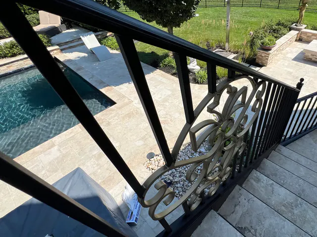 Finished black exterior railing overlooking a stone patio.